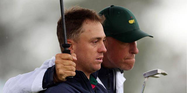 Justin Thomas of the United States and his caddie Jim "Bones" Mackay react to his bogey on the 18th green during the continuation of the weather-delayed second round of the 2023 Masters Tournament at Augusta National Golf Club April 8, 2023, in Augusta, Ga.