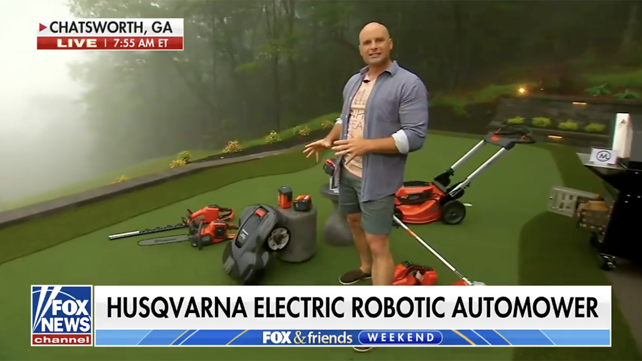 Chip Wade next to a robotic lawnmower