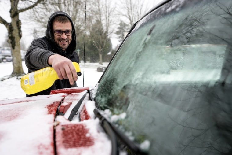 Brian Elsey cleans off his boss's car before heading home  in Portland, Ore., on Jan. 13, 2024. 